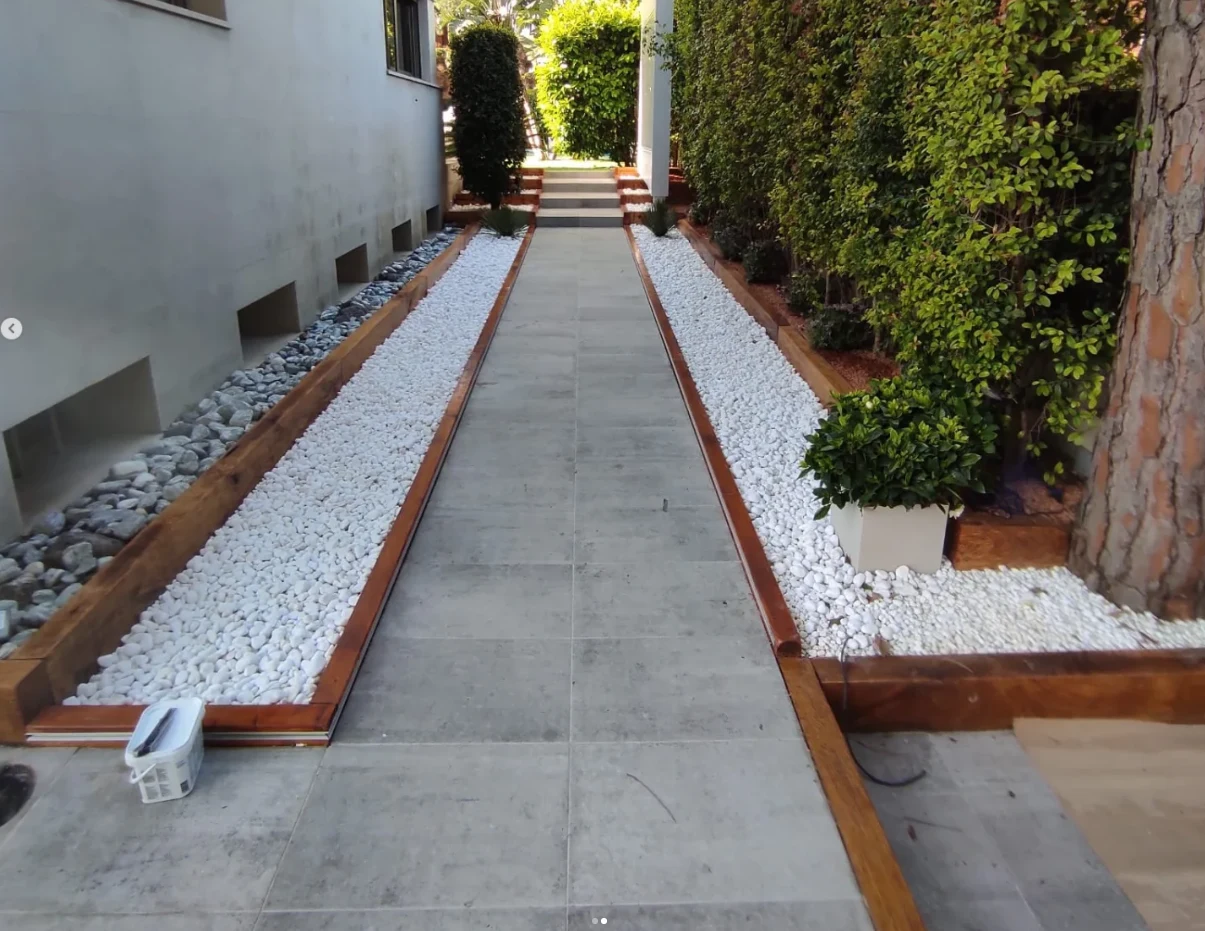Camino exterior acabado con pavimento, piedra blanca y bordes de madera